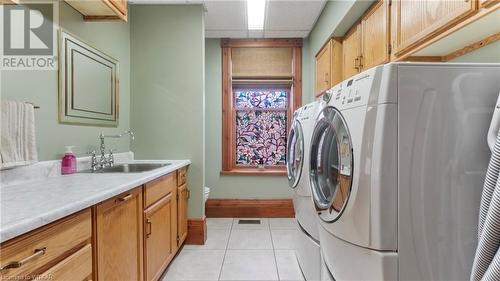 Clothes washing area featuring separate washer and dryer, sink, light tile patterned floors, and cabinets - 246 Light Street, Woodstock, ON - Indoor Photo Showing Laundry Room