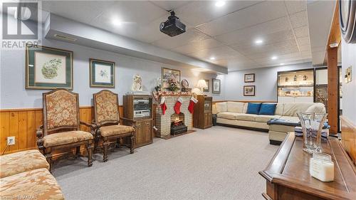 Living room featuring carpet, a drop ceiling, a fireplace, and wooden walls - 246 Light Street, Woodstock, ON - Indoor