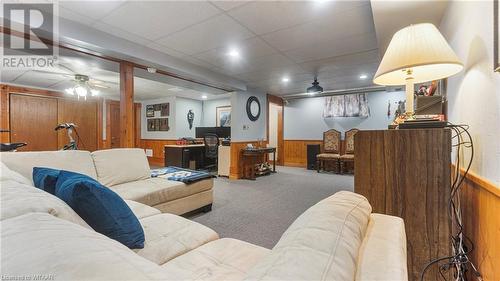 Living room featuring carpet flooring, ceiling fan, a drop ceiling, and wooden walls - 246 Light Street, Woodstock, ON - Indoor