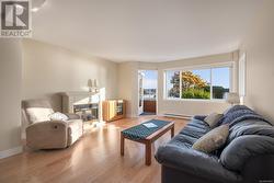 Living room with a baseboard heating unit and light wood-type flooring - 