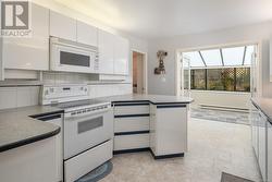 Kitchen with white appliances, white cabinetry, a baseboard radiator, and decorative backsplash - 