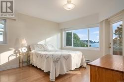 Bedroom with light hardwood / wood-style flooring, a baseboard heating unit, and a water view - 