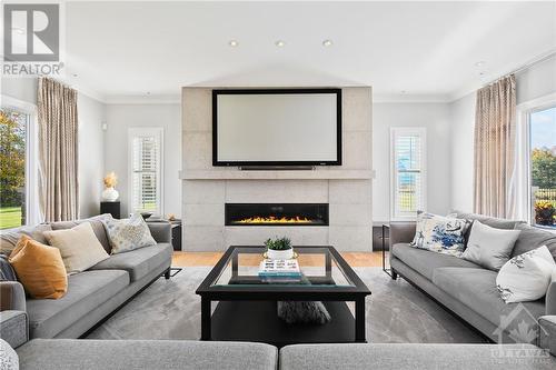 Custom floor to ceiling feature wall with linear gas fireplace and 100' screen with projector. Built-in benches with drawers on either side all surrounded by windows over-looking the expansive yar - 144 Kerry Hill Crescent, Ottawa, ON - Indoor Photo Showing Living Room With Fireplace