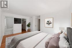 Virtually staged primary bedroom with view of ensuite and walk-in closet - 