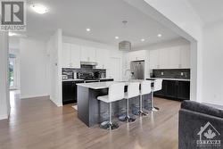 Large kitchen with island, breakfast bar, white cabinetry and quartz counter tops. - 