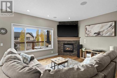 Adjacent to the kitchen is the spacious living room complete with a Valor corner fireplace - 209 Hidden Creek Road Nw, Calgary, AB - Indoor Photo Showing Living Room With Fireplace