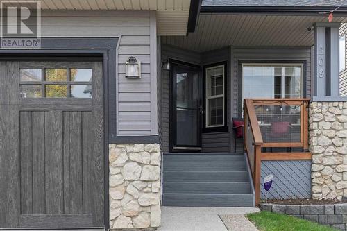 This home has amazing curb appeal with a terrific blend of exposed aggregate, stone and vinyl siding exteriors, and a premium garage door - 209 Hidden Creek Road Nw, Calgary, AB - Outdoor