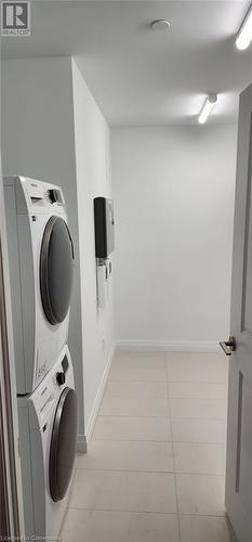 Clothes washing area with light tile patterned floors and stacked washer and dryer - 525 New Dundee Road Unit# 602, Kitchener, ON - Indoor Photo Showing Laundry Room