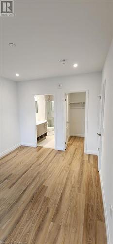 Unfurnished bedroom with light wood-type flooring, connected bathroom, a closet, and a walk in closet - 525 New Dundee Road Unit# 602, Kitchener, ON - Indoor