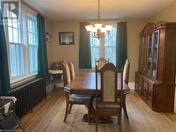 Dining room with light wood-type flooring, radiator heating unit, and a chandelier - 