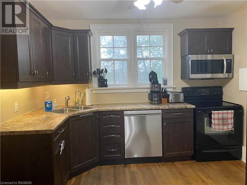 Kitchen featuring dark brown cabinetry, appliances with stainless steel finishes, sink, and hardwood / wood-style flooring - 76 10Th Street, Hanover, ON - Indoor Photo Showing Kitchen With Double Sink