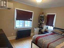 Bedroom featuring radiator, a wall mounted AC, and light hardwood / wood-style flooring - 