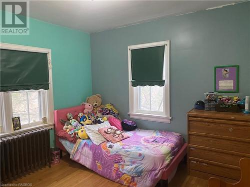 Bedroom featuring radiator, multiple windows, and hardwood / wood-style floors - 76 10Th Street, Hanover, ON - Indoor Photo Showing Bedroom