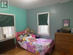 Bedroom featuring radiator, multiple windows, and hardwood / wood-style floors - 