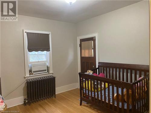 Bedroom featuring a crib, light hardwood / wood-style floors, and radiator - 76 10Th Street, Hanover, ON - Indoor Photo Showing Bedroom