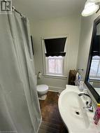 Bathroom with curtained shower, tile patterned floors, toilet, and sink - 