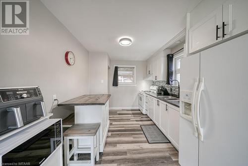 Kitchen with white cabinetry, white appliances, and light hardwood / wood-style floors - 824 Devonshire Avenue, Woodstock, ON - Indoor Photo Showing Kitchen