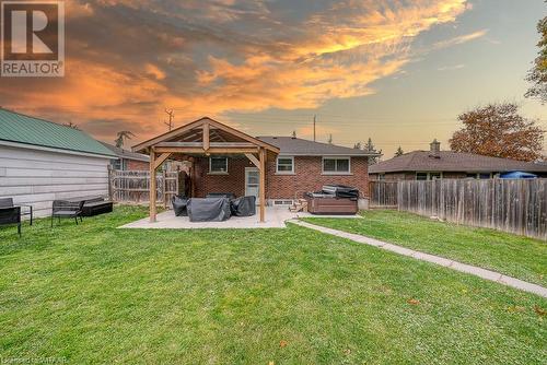 Back house at dusk featuring a patio, a hot tub, and a lawn - 824 Devonshire Avenue, Woodstock, ON - Outdoor