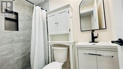 Bathroom with toilet, a shower with curtain, and vanity - 