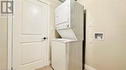 Clothes washing area featuring light hardwood / wood-style floors and stacked washer and dryer - 