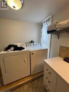 Clothes washing area featuring washer and clothes dryer and dark tile patterned floors - 