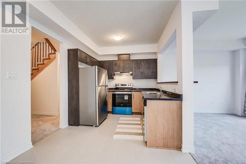 Kitchen with stainless steel appliances, light colored carpet, sink, and dark brown cabinetry - 26 Elsegood Drive, Guelph, ON - Indoor Photo Showing Kitchen