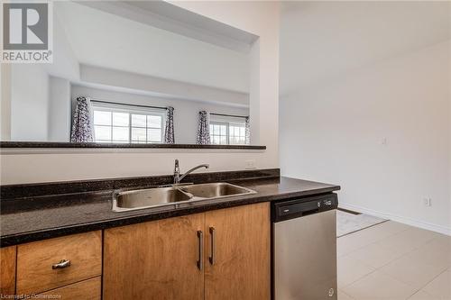 Kitchen featuring dishwasher, sink, dark stone countertops, and light tile patterned floors - 26 Elsegood Drive, Guelph, ON - Indoor Photo Showing Kitchen With Double Sink