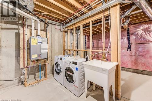 Basement with tankless water heater, sink, and washer and clothes dryer - 26 Elsegood Drive, Guelph, ON - Indoor Photo Showing Laundry Room