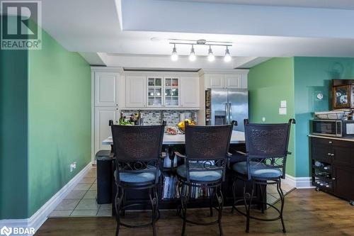 Kitchen with stainless steel appliances, wood-type flooring, decorative backsplash, a breakfast bar area, and white cabinetry - 145 Farley Avenue Unit# 103, Belleville, ON - Indoor