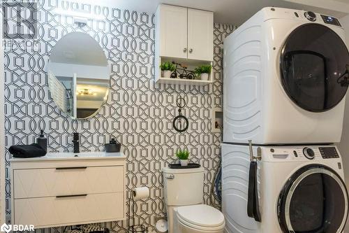 Clothes washing area featuring stacked washing maching and dryer and sink - 145 Farley Avenue Unit# 103, Belleville, ON - Indoor Photo Showing Laundry Room