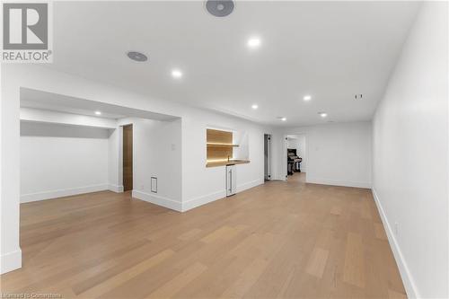 Media room. Wine bar on left, wet bar mid-frame. Large bathroom rear left. Bedroom/office/den rear center. White oak flooring throughout. Utility room. - 5427 Anthony Place, Burlington, ON - Indoor Photo Showing Other Room