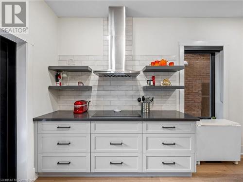 Kitchen on main-floor: built-in cook-top with hood vent, built-in oven, quartz countertops, patterned subway tile backsplash - 213 Caroline Street S, Hamilton, ON 