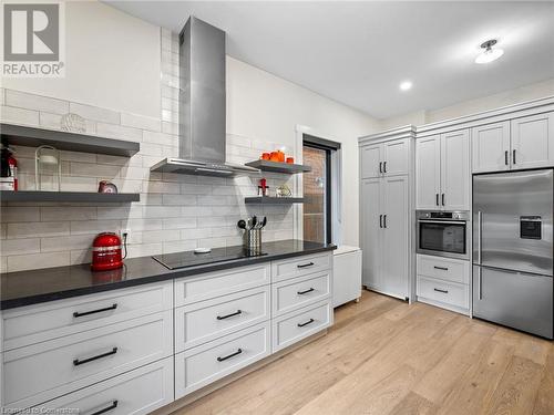 Kitchen on main-floor: built-in cook-top with hood vent, built-in oven, quartz countertops, patterned subway tile backsplash - 213 Caroline Street S, Hamilton, ON 