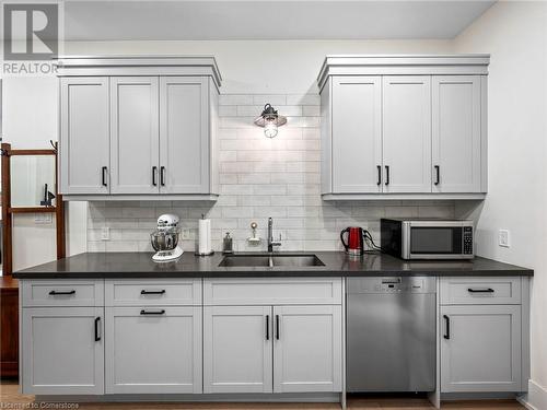 Kitchen on main-floor: double undermount sink, quartz countertops, patterned subway tile backsplash, Miele dishwasher - 213 Caroline Street S, Hamilton, ON 