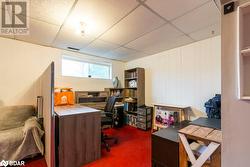 Office area featuring a drop ceiling, carpet flooring, and wooden walls - 