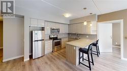 Kitchen with stainless steel appliances, kitchen peninsula, a breakfast bar, pendant lighting, and white cabinetry - 