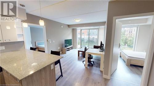 Kitchen with white cabinetry, light wood-type flooring, a healthy amount of sunlight, and decorative light fixtures - 308 Lester Street Unit# 215, Waterloo, ON - Indoor