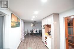 Kitchen featuring white cabinets, light hardwood / wood-style flooring, and decorative light fixtures - 