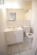 Bathroom featuring toilet, vanity, tile walls, and tile patterned floors - 