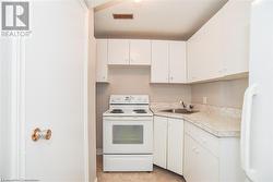 Kitchen with white appliances, sink, and white cabinets - 