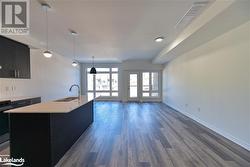 Kitchen with dark hardwood / wood-style floors, sink, a kitchen island with sink, and decorative light fixtures - 