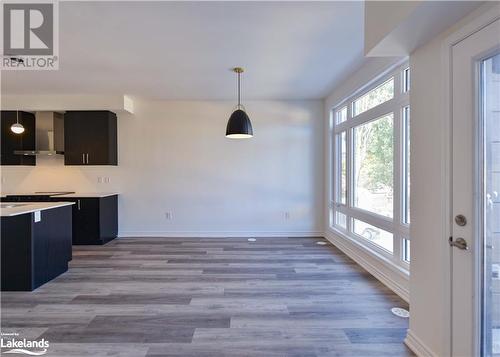 Kitchen featuring hanging light fixtures, light hardwood / wood-style floors, and wall chimney range hood - 25 Wyn Wood Lane, Orillia, ON - Indoor Photo Showing Kitchen