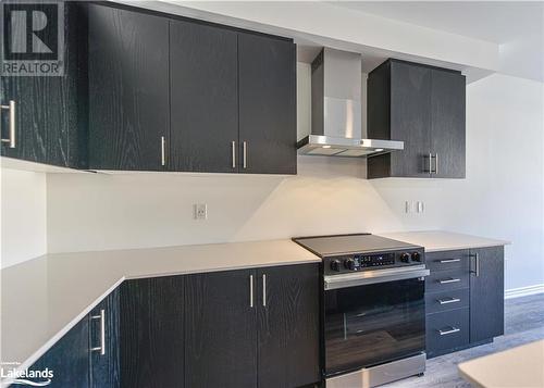 Kitchen featuring light wood-type flooring, wall chimney exhaust hood, and stainless steel range with electric cooktop - 25 Wyn Wood Lane, Orillia, ON - Indoor Photo Showing Kitchen