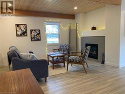 Living room with light  floors, a tiled fireplace, wood ceiling, and beam ceiling - 