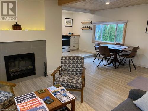 Living room with wooden ceiling, a tiled fireplace, and light wood-style flooring - 2 John Street, Lions Head, ON - Indoor Photo Showing Other Room With Fireplace