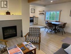 Living room with wooden ceiling, a tiled fireplace, and light wood-style flooring - 