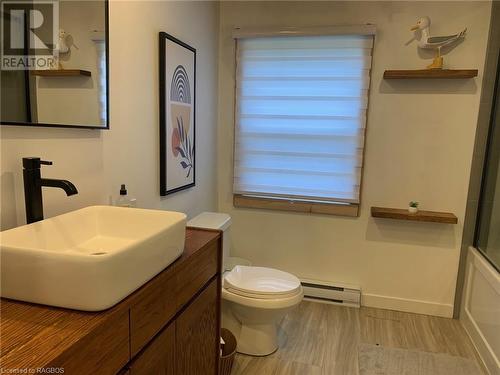 Full bathroom featuring a baseboard heating unit, enclosed tub / shower combo, toilet, hardwood / wood-style floors, and vanity - 2 John Street, Lions Head, ON - Indoor Photo Showing Bathroom