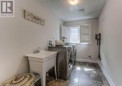 Laundry area with dark tile patterned flooring, independent washer and dryer, and a textured ceiling - 