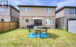 Rear view of property featuring a lawn, a patio, and a garage - 