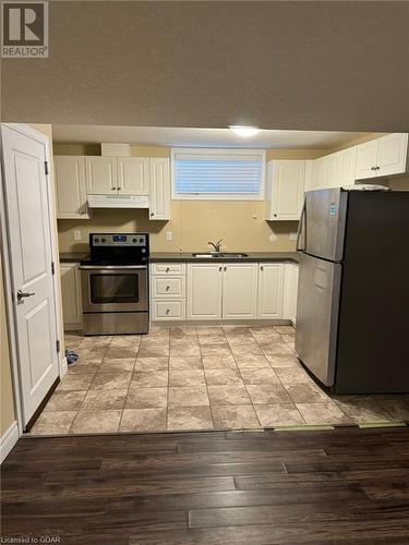 Kitchen with white cabinetry, appliances with stainless steel finishes, sink, and light hardwood / wood-style flooring - 111 Dallan Drive, Guelph, ON - Indoor Photo Showing Kitchen With Double Sink